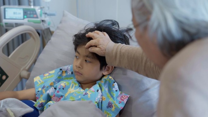 在医院，一位祖母在临睡前抚摸着躺在床上的小男孩的头