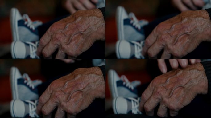 爷爷在家里抱着小男孩的腿，满是皱纹的手特写