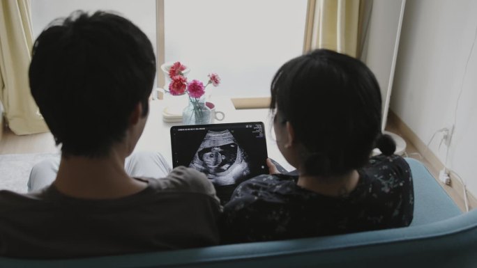 一对夫妇正在看电子平板电脑上的超声波视频
