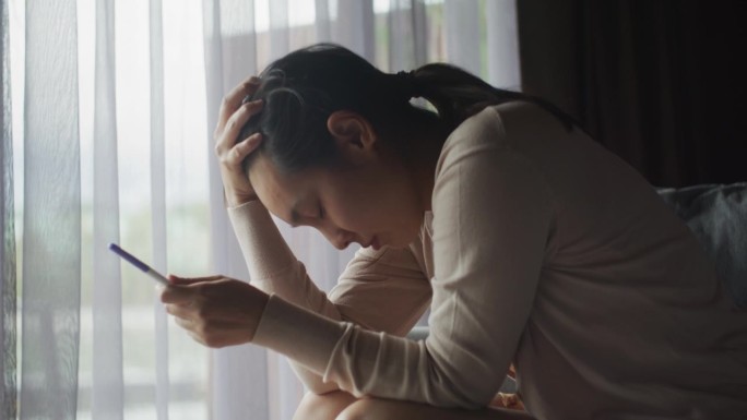 年轻女子在家里做了孕检后看起来很沮丧