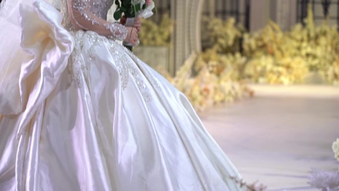 身穿白色婚纱的新娘站在仪式大厅的舞台上