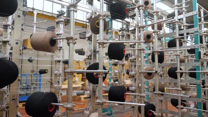 线轴上。纺织工业。纺织工厂。有许多线轴的机架。为进一步生产织物而对纱线进行染色和干燥。自动化的工作流