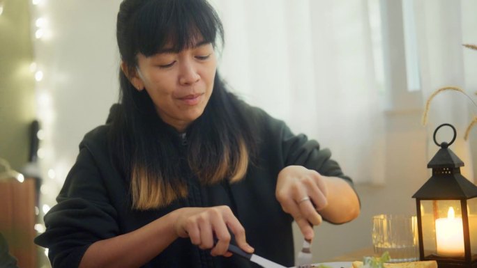 年轻的亚洲妇女吃着牛排，和她的朋友谈论美味的饭菜。