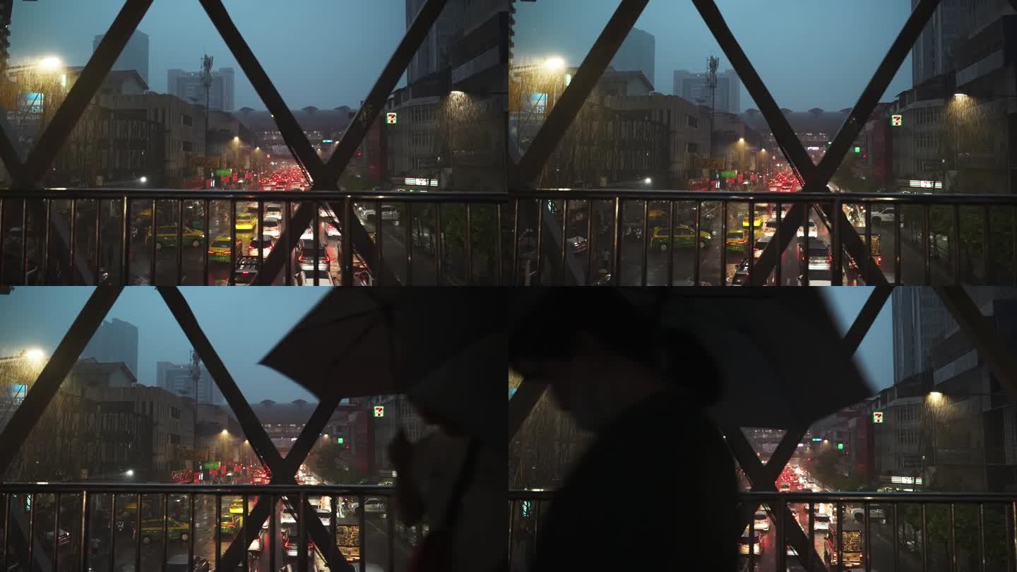 雨夜城市道路上的人行天桥。前景中打着伞的人们的剪影