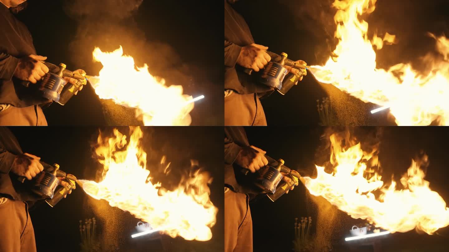 特技演员在夜间使用燃烧的火炬和气雾剂罐制造大火