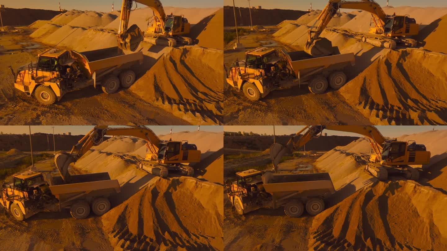 空中无人机拍摄的建筑工地在阳光明媚的晚上:工业挖掘机装载沙子到一辆卡车。建设新公寓大楼的过程。操作重