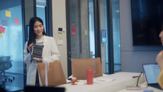 亚洲女商人向办公室同事介绍太阳能电池板的特性。