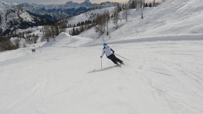 一名无法辨认的女子在雪山滑雪胜地的修整过的斜坡上滑雪