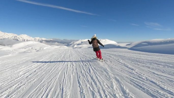 女士滑雪板在一个风景优美的滑雪斜坡与雪山的壮丽景色