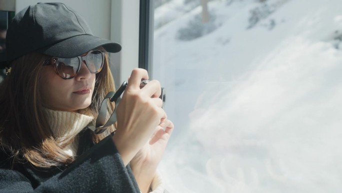 一位亚洲女摄影师在瑞士山区乘火车旅行时，正在拍摄美丽的山景。