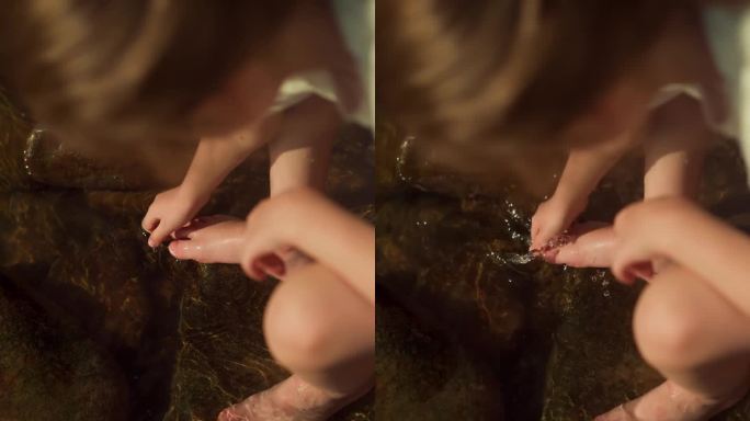 小女孩坐在岩石上用河水洗脚