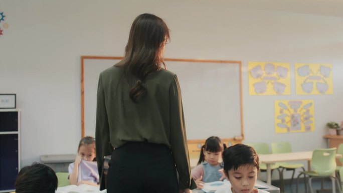 微笑的亚洲女教师和学生们在课桌之间走着。