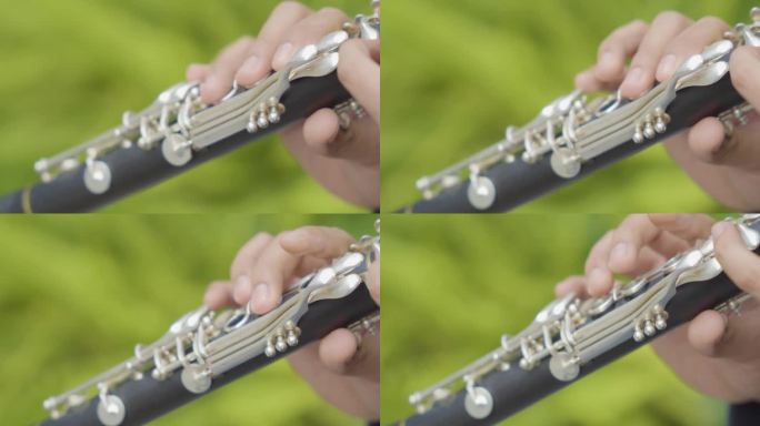 一个男人的手指演奏单簧管与绿色模糊背景的特写。