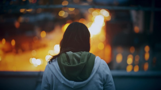 晚上戴着耳机在城市屋顶上听音乐的女人