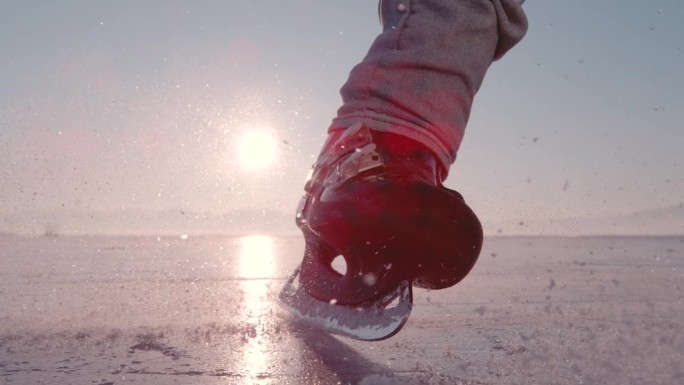 镜头光晕，超慢动作，特写:一名男子滑冰停在冰冻的湖面上