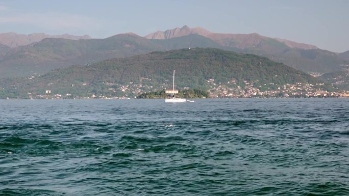 一艘收起帆的帆船驶过马焦雷湖。意大利皮埃蒙特，从斯特雷萨望向韦尔巴尼亚