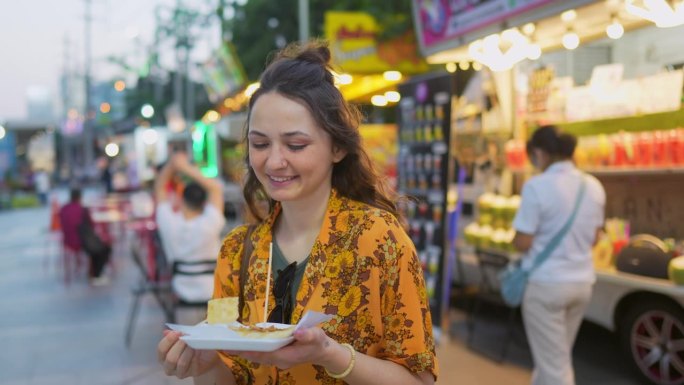 度假期间，一名女子在曼谷夜市吃泰国煎饼(roti)