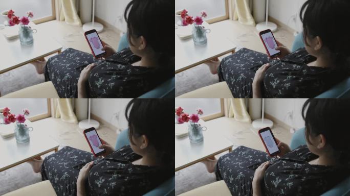 年轻的母亲在智能手机上看婴儿的衣服