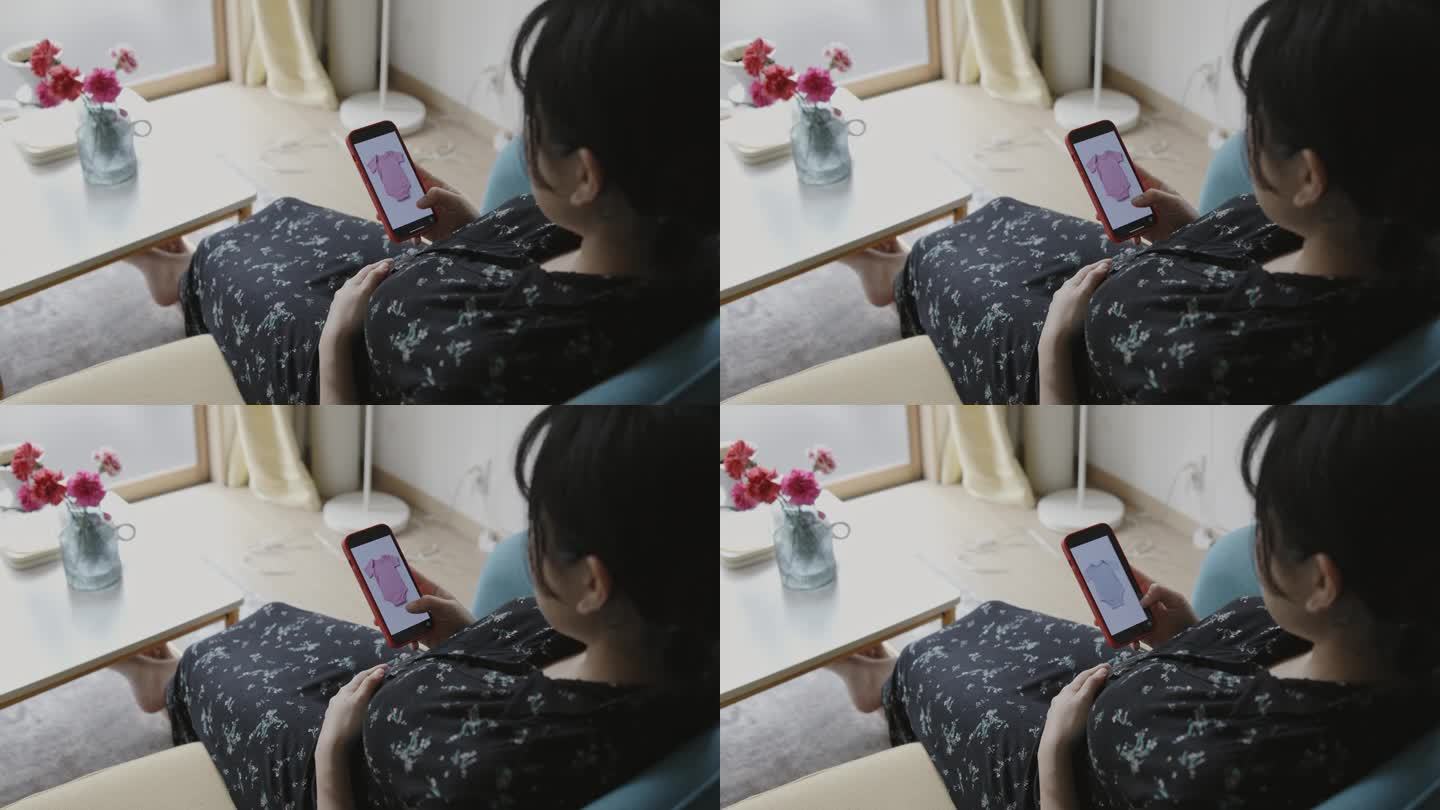 年轻的母亲在智能手机上看婴儿的衣服