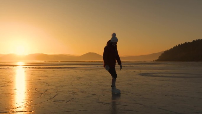 镜头光晕，剪影:一个寒冷的冬日，一个女人在金色的阳光下滑冰