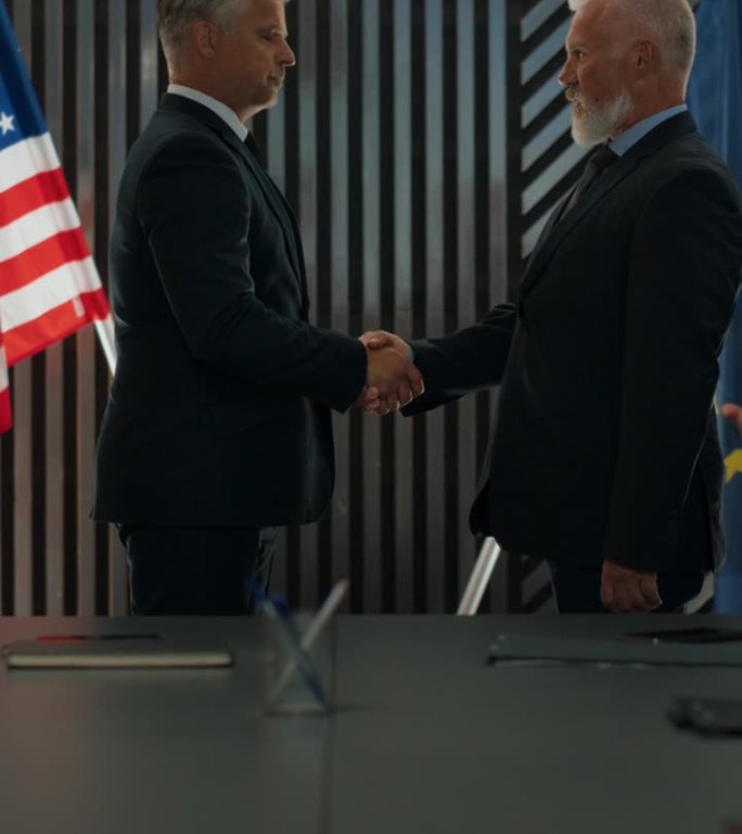 高层政治论坛竖屏:两位来自欧盟和美国的白人男性政治家成功握手。代表们为会议成功达成协议而鼓掌。