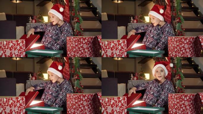 小男孩戴着圣诞老人的帽子，打开圣诞礼盒，兴奋而快乐。寒假的家庭庆祝活动。