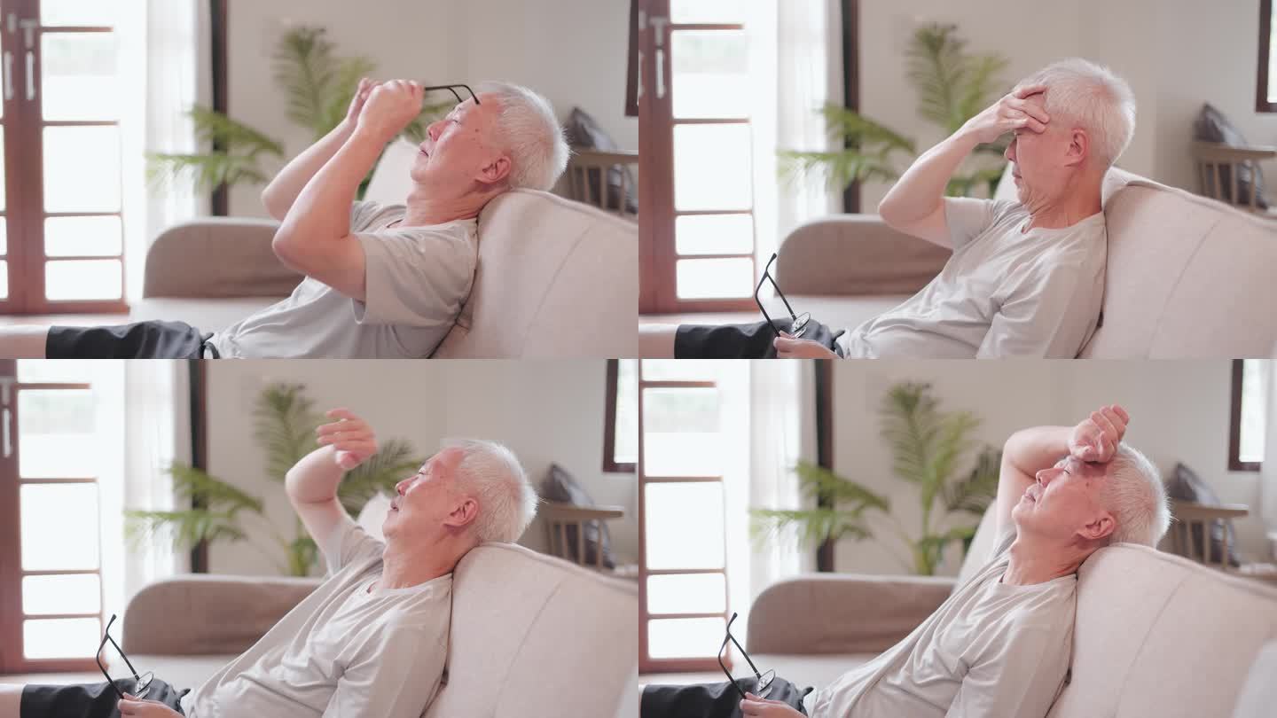 亚洲老年男性坐在家里的沙发上头痛，工作压力大，痛苦和悲伤，无法入睡