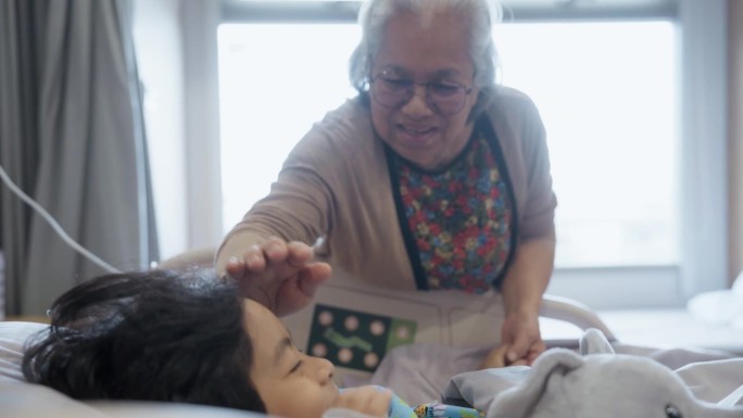 在医院的康复室里，一位祖母抚摸着孙子的头，安慰他。