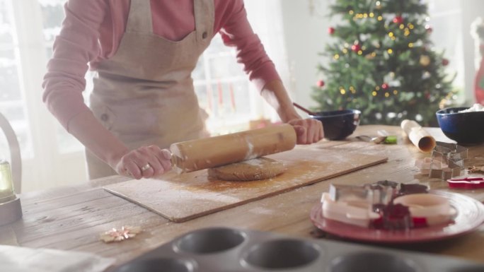 动态荷兰角度:放大慢动作的年轻女子准备面团做姜饼在圣诞节。慈爱的母亲为她的家人准备节日的糕点