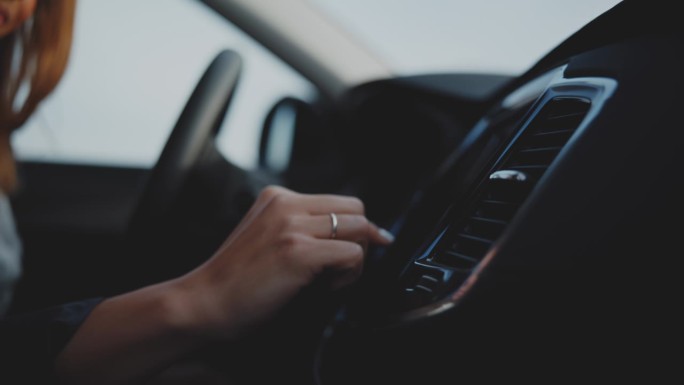 近距离的妇女使用触摸屏仪表盘在停放的汽车