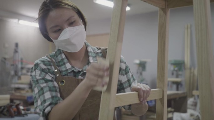 木工车间里用锯子锯木头的女木匠