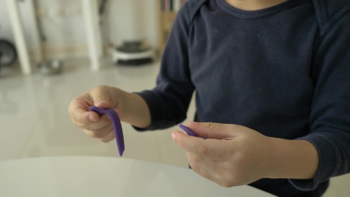 特写小男孩在家里玩橡皮泥面团的手，慢镜头
