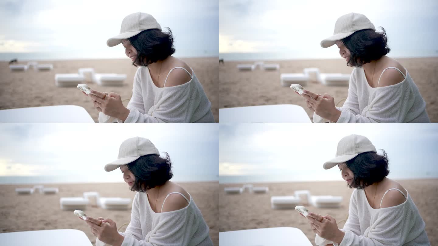 亚洲女游客在海边度假观光。她喜欢用智能手机为她的旅游博客做笔记。放松,享受。他微笑着，看起来很开心。