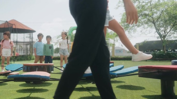 多样的孩子在幼儿园和年轻的女老师一起玩体育游戏。