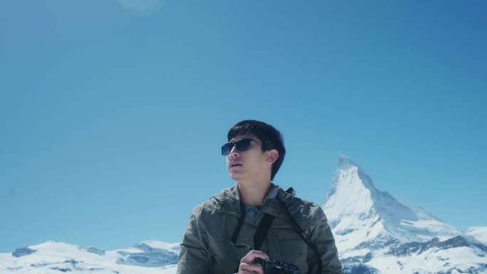 一个年轻的摄影师在瑞士的雪山度假，在他的空闲时间散步和拍照。