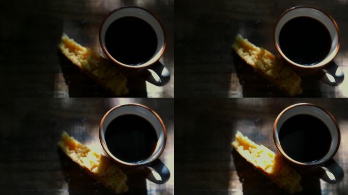 一个咖啡杯和一块蛋糕放在阳光下的桌子上。随机的阳光照在咖啡上。阳光照在桌子上。阳光照在蛋糕上。喝咖啡