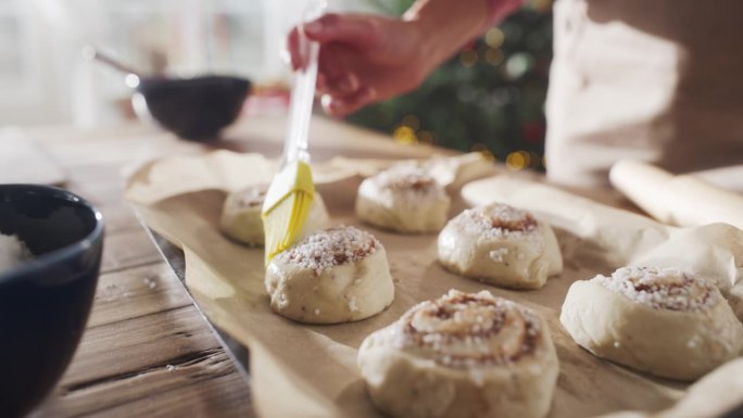 慢动作特写的手，一个匿名的女性制作糕点与家人和朋友分享圣诞节。为节日晚上的客人准备的美味面包涂上黄油