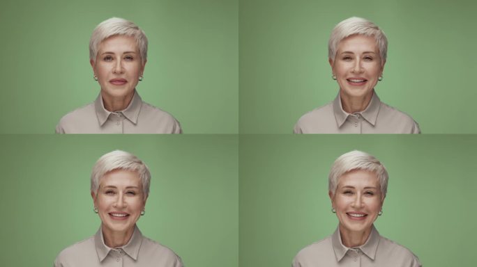 在彩色工作室拍摄的成年妇女看着相机微笑的肖像。孤独的老妇人绿色背景特写。上了年纪的人，涂着时髦的化妆