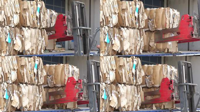 带捆夹的叉车在回收中心拾取纸张和纸板。