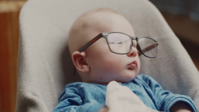 可爱的小男孩戴着眼镜在家里的保镖旁休息时呕吐牛奶的特写。有趣的场景