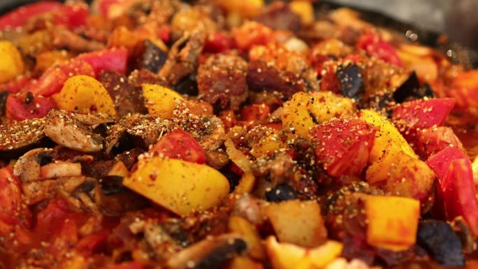 土豆与蔬菜、蘑菇、茄子、肉和香料一起在火上炸。