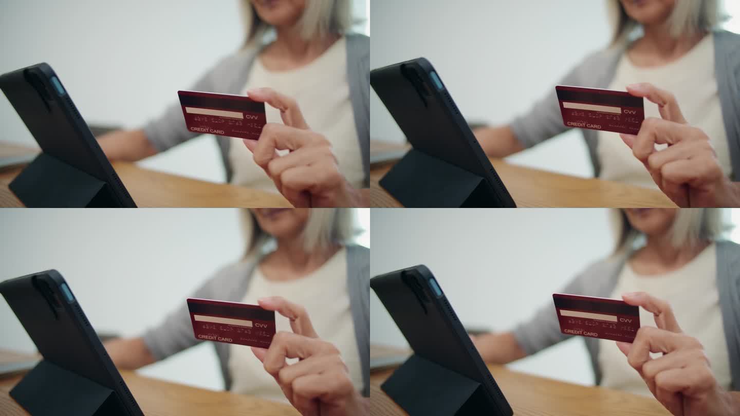老妇人用数码平板电脑和信用卡购物