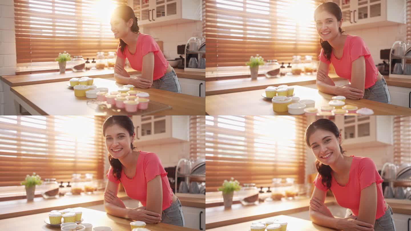 女人在厨房里微笑着展示新鲜的纸杯蛋糕，慢镜头