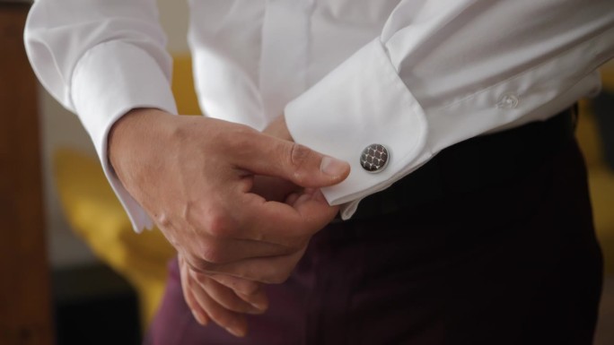 扣西装扣子。婚礼前，手在调整用袖扣系住的衬衫袖口。