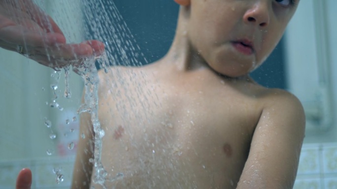 洗澡时，水从淋浴喷头流入孩子的身体，父母在日常生活中为孩子洗澡