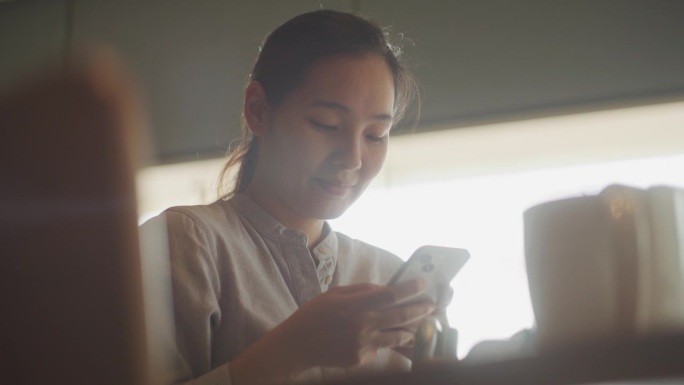 女性使用智能手机看消息发笑亚洲美女办公室