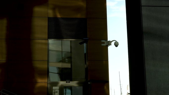 有金色反光窗和阴影的大楼上的监控摄像头。
