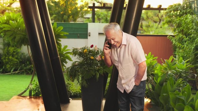 快乐的印度老人，白发老人走在户外，拿着手机享受有趣愉快的谈话。老一辈人利用现代无线技术进行远程通信