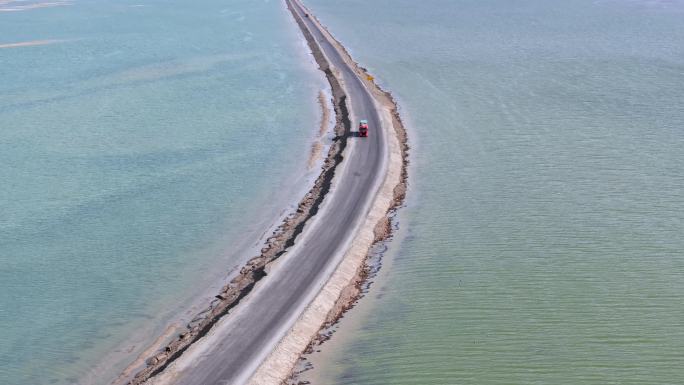 航拍货车行驶在青海西台吉乃尔湖中的公路上