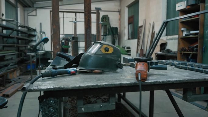 照明工厂工作台上焊接头盔及工具的SLO - MO特写